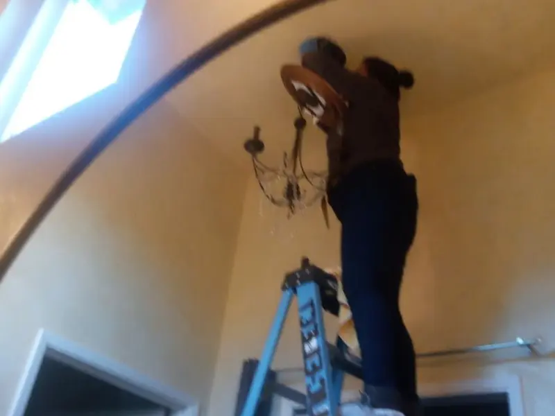 Electrician installing a chandelier in a Orem residence
